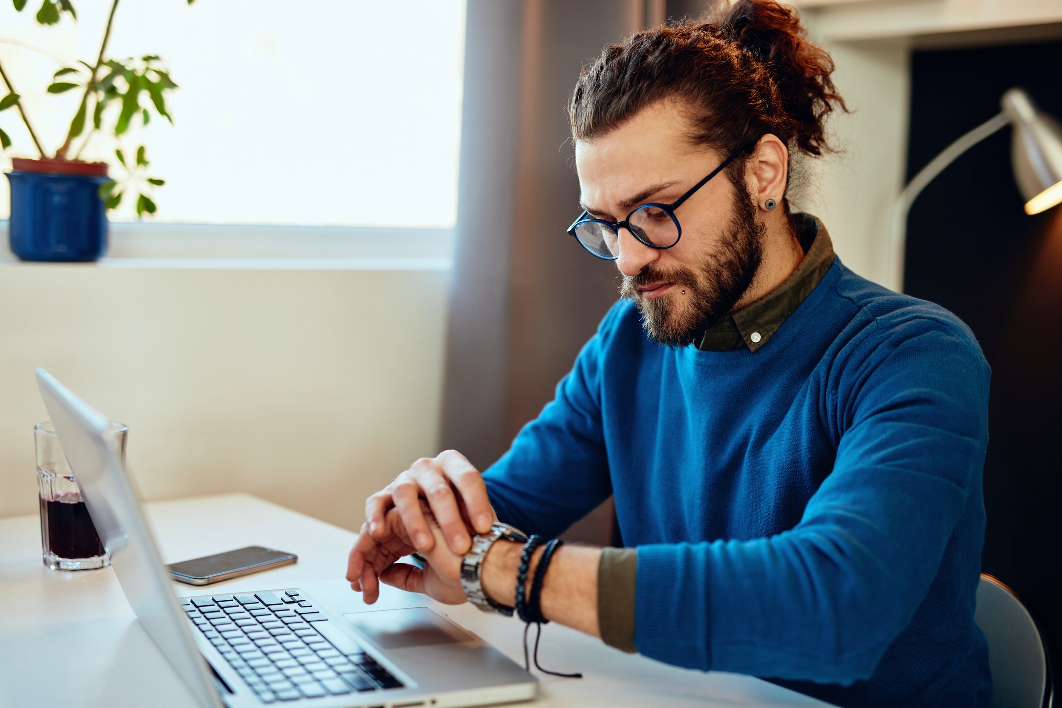 person looking at their watch while working at a laptop person looking at their watch while working at a laptop